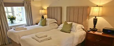 a hotel room with two beds and a window at The Coach House at Lodge Farm with Hot Tub in Hilgay