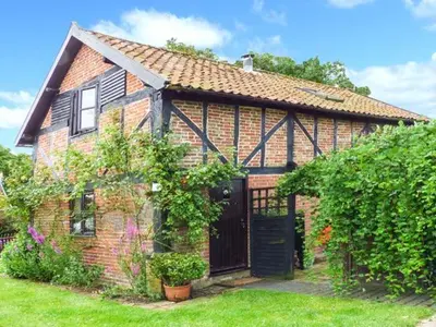 a brick house with a black door in a yard at The Granary in Norwich