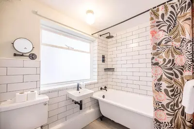 a white bathroom with a sink and a bath tub and a window at The Shealing, Waldringfield in Waldringfield