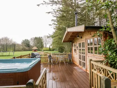 a large wooden deck with a table and a grill at Someplace Else in Diss
