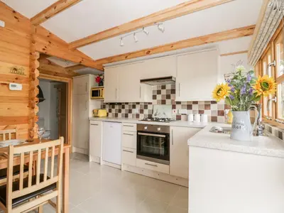 a kitchen with white cabinets and a vase of flowers at Someplace Else in Diss