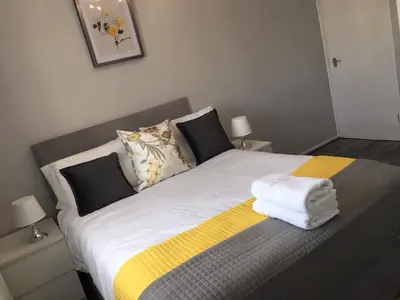 a bedroom with a bed with a yellow and white blanket at Peaceful 3 Bed Home in Basildon