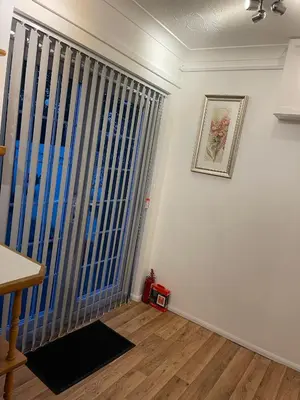 a living room with a large window with vertical blinds at Peaceful 3 Bed Home in Basildon