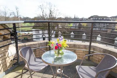 a table with chairs and a vase of flowers on a balcony at Citystay Living - Marino Place in Cambridge