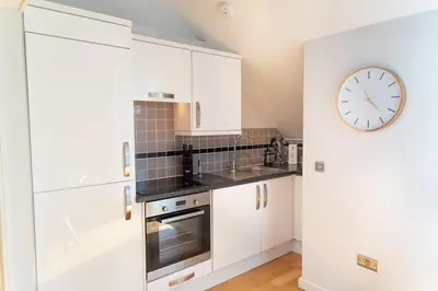 a kitchen with white cabinets and a clock on the wall at Citystay Living - Marino Place in Cambridge