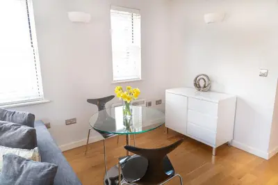 a living room with a glass table and a chair at Citystay Living - Marino Place in Cambridge