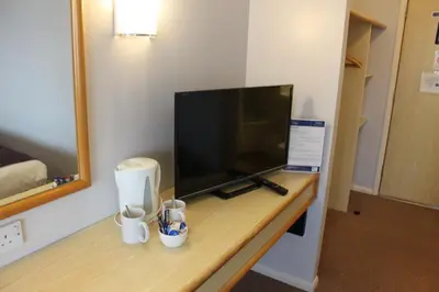 a room with a desk with a flat screen tv at Redwings Lodge Baldock in Baldock