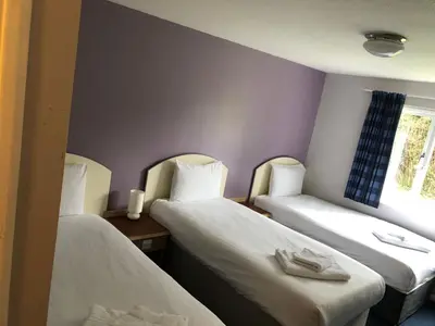 a room with two beds and a window at Redwings Lodge Baldock in Baldock
