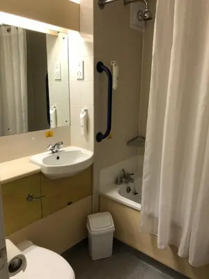 a bathroom with a sink and a toilet and a mirror at Redwings Lodge Baldock in Baldock