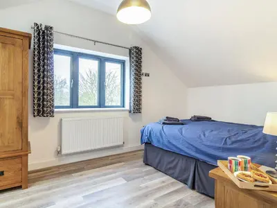 a bedroom with a blue bed and a window at Fenside Way in Wicken