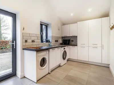 a kitchen with white cabinets and a washer and dryer at Fenside Way in Wicken