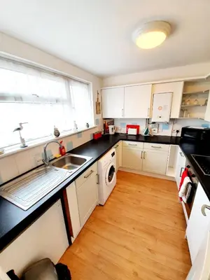 a kitchen with white cabinets and a sink and a window at Rayleigh Town Centre 2 Bedroom Apartment in Rayleigh