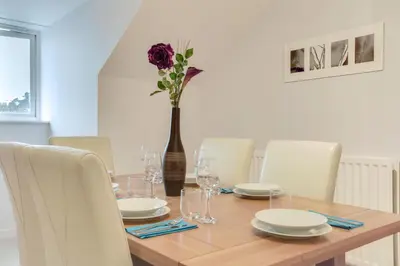 a dining room table with a vase with a flower at Modern Spacious Apartments in Bishops Stortford