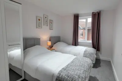 two beds in a room with a window at Modern Spacious Apartments in Bishops Stortford