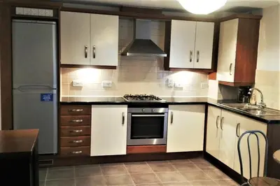 a kitchen with white cabinets and a stove top oven at Modern Spacious Apartments in Bishops Stortford
