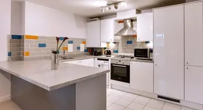 a kitchen with white cabinets and a counter top at Modern Spacious Apartments in Bishops Stortford