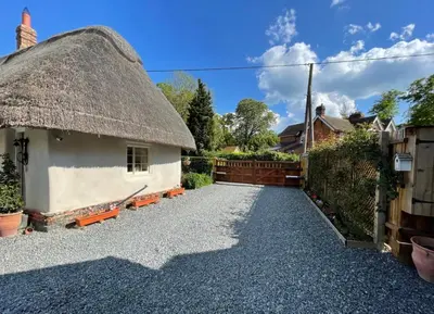 a thatch roofed house with a gravel driveway at The Cottage get away in Saffron Walden