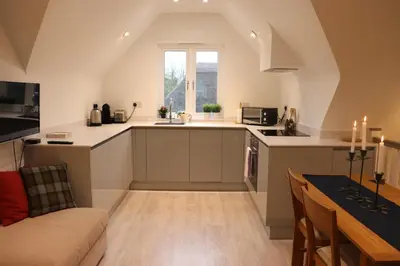 an attic kitchen with a couch and a table at The Cottage get away in Saffron Walden