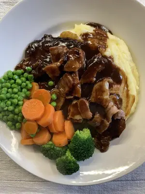 a plate of food with meat and vegetables on a table at Ye Olde White Harte Hotel in Burnham on Crouch