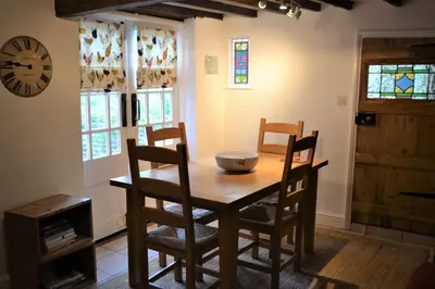a dining room with a table and chairs and a clock at Appletree Cottages in Mildenhall