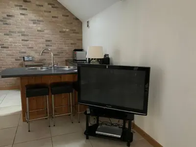 a flat screen tv sitting on a stand next to a kitchen at Appletree Cottages in Mildenhall