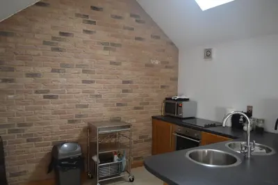 a kitchen with a brick wall and a sink at Appletree Cottages in Mildenhall