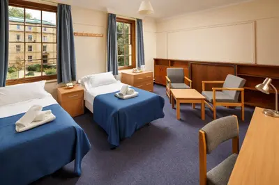 a hotel room with two beds and a table and chairs at Christ's College Cambridge in Cambridge