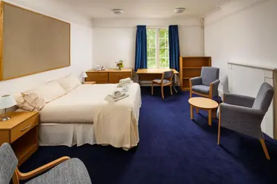 a hotel room with a bed and two chairs at Christ's College Cambridge in Cambridge