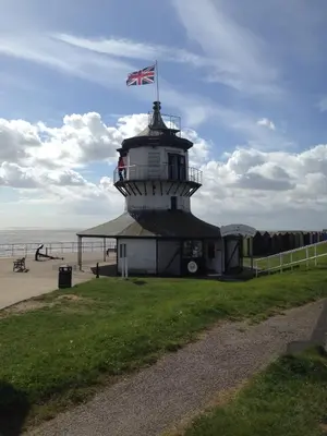a lighthouse with a flag on top of it on the beach at The Bakehouse in Harwich