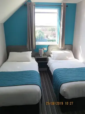 two beds in a room with a window at Oyster Fleet Hotel in Canvey Island