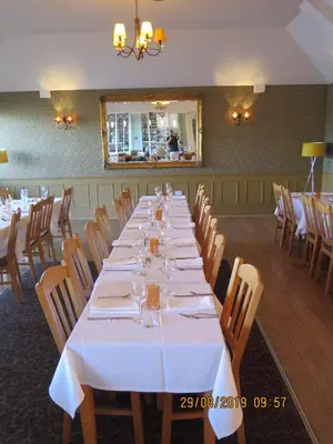 a long table in a restaurant with white tables and chairs at Oyster Fleet Hotel in Canvey Island