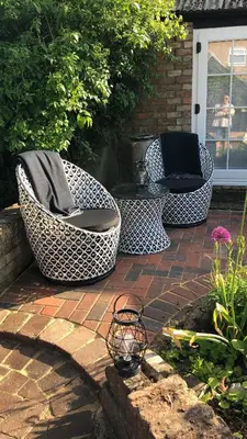three wicker chairs and a table on a patio at The Blue Cow in Fenstanton