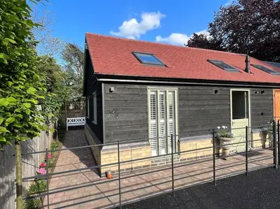 a small house with a red roof and a fence at The Nest-Cambridge in Cambridge