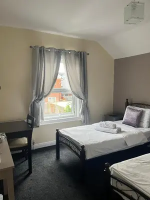 a bedroom with two beds and a window at The Harp Freehouse and Guesthouse in Ipswich