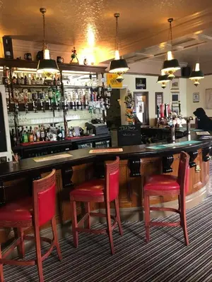 a bar with four red chairs and a counter at The Harp Freehouse and Guesthouse in Ipswich