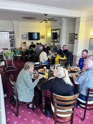 a group of people sitting at a table eating food at The Harp Freehouse and Guesthouse in Ipswich