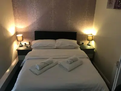 a large white bed with two towels on it at The Harp Freehouse and Guesthouse in Ipswich