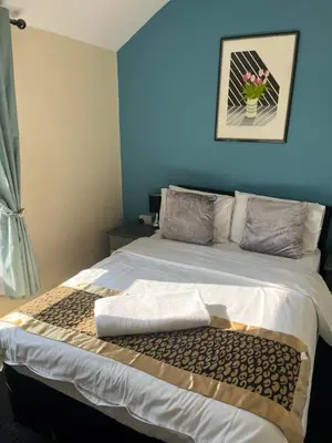 a bedroom with a large bed with a blue wall at The Harp Freehouse and Guesthouse in Ipswich