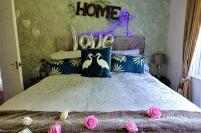 a bedroom with a bed with a home sign on the wall at Lakeland Lodge with private Hot Tub and fishing in Hatfield Peverel