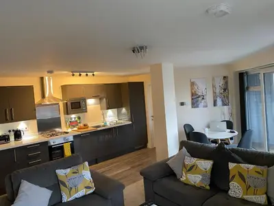 a living room with two couches and a kitchen at 13 The Grosvenor, luxury flat, central Newmarket, in Newmarket