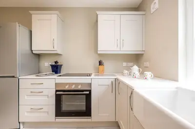 a white kitchen with white cabinets and an oven at The Dower Lodge in Sizewell