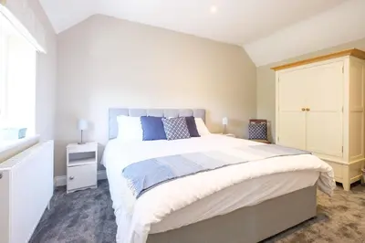 a bedroom with a large bed and a white cabinet at The Dower Cottage in Sizewell
