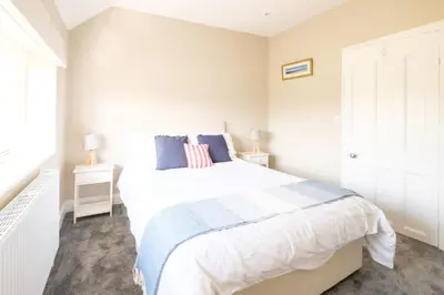 a white bedroom with a large bed and a window at The Dower Cottage in Sizewell