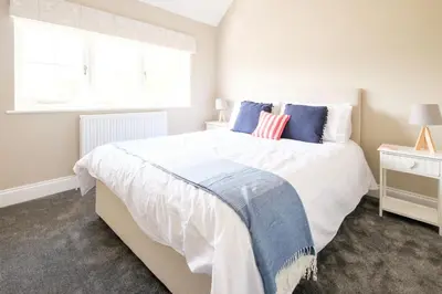 a bedroom with a large white bed with blue pillows at The Dower Cottage in Sizewell