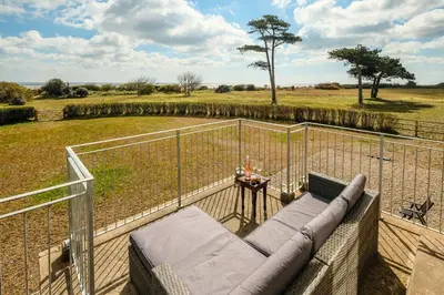 a balcony with a couch and a fence and a field at The Dower House in Sizewell