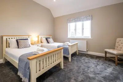 a bedroom with two beds and a chair and a window at The Dower House in Sizewell