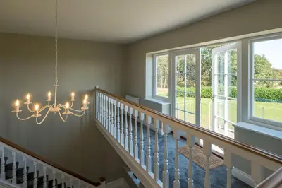 a staircase in a home with a chandelier at The Dower House in Sizewell