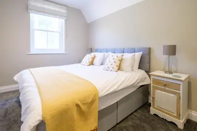 a bedroom with a bed with a yellow blanket on it at The Dower Retreat in Sizewell