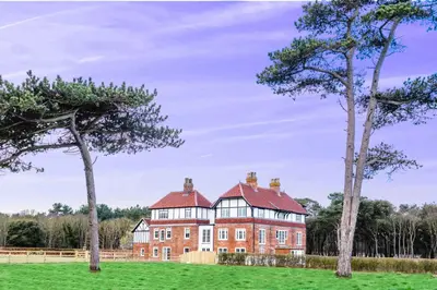 a large red brick house with trees in the foreground at The Dower Retreat in Sizewell