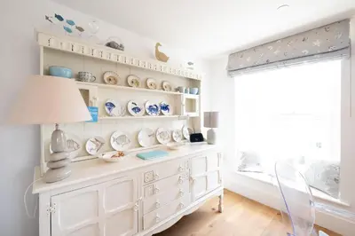 a room with a white dresser with plates on it at Mansard House in Aldeburgh